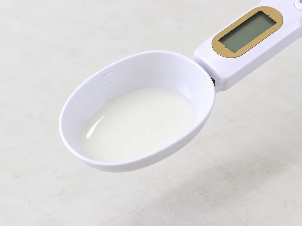 A close overhead-oblique photograph of the exact white spoon bowl containing a shallow amount of cle